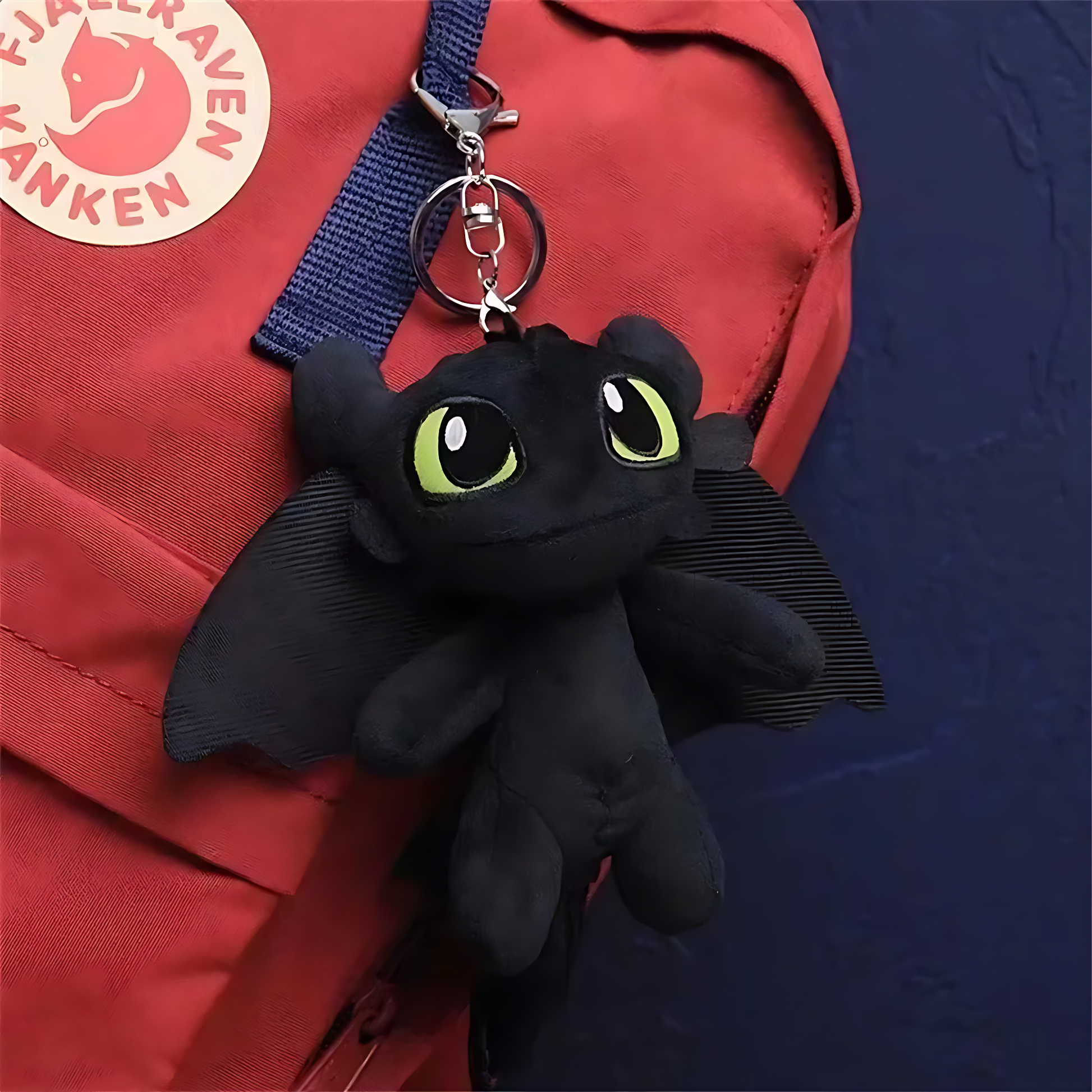 Black plush dragon keychain attached to a red backpack